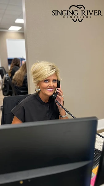 A receptionist scheduling the appointment at Singing River Dentistry.