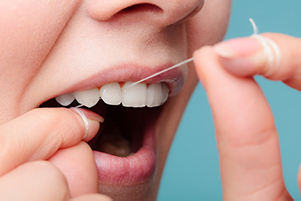 Image of a person flossing their teeth to prevent tooth loss at at Singing River Dentistry in Florence, AL 