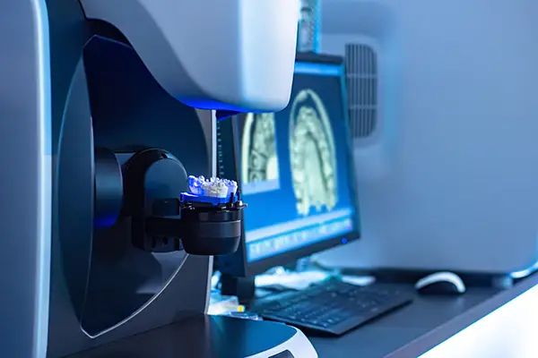 A high-tech dental scanner used for designing same-day crowns with a 3D model displayed on a monitor.