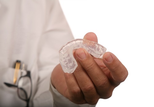 dentist holding an oral appliance made for bruxism at Singing River Dentistry