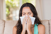 Woman blowing her nose in a tissue