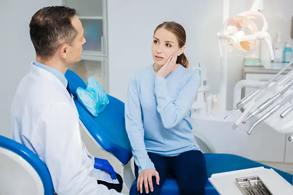 Patient holding side on mouth speaking with dentist atSinging River Dentistry in Florence, AL