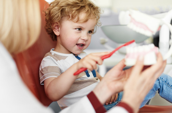 Little boy learning to brush teeth after visiting Singing River Dentistry