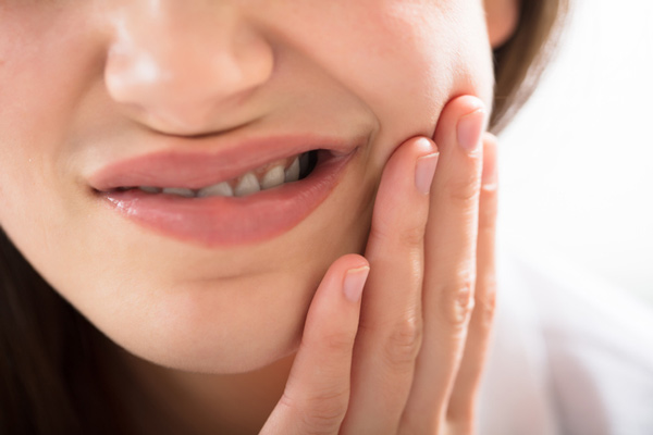 A woman with gum disease holding her jaw at Singing River Dentistry in Muscle Shoals, AL A woman with gum disease holding her jaw at Singing River Dentistry in Muscle Shoals, AL