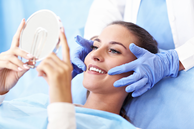 A woman looking at her teeth from Singing River Dentistry in Florence, AL