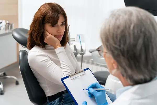 Female patient consulting with a dentist about severe tooth pain during an emergency dental appointment in a clinic.