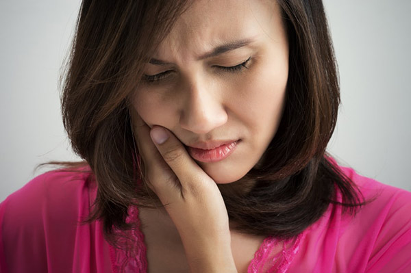 Woman suffering from pain and holding her jaw